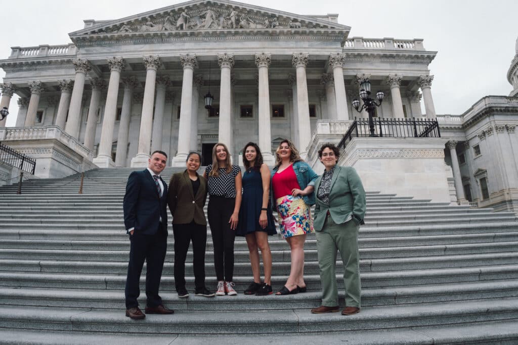 Group of diverse young adults standing together on Capitol Hill, engaged in conversation and activism, showcasing unity and civic participation.